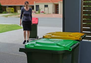 Woman taking garbage cans to side of road